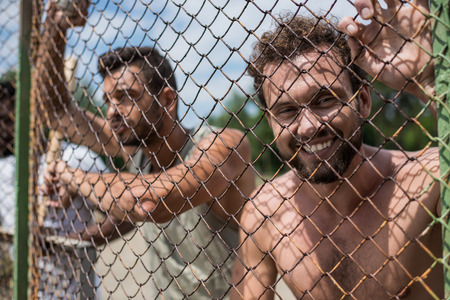 young men leaning on fence during baseball gameの写真素材