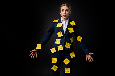 overworked middle aged businesswoman standing with sticky notes on suitの写真素材