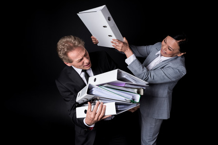 excited asian businesswoman with folder fighting with scared businessman holding folders
