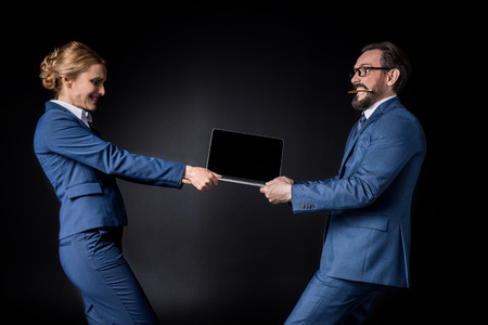side view of middle aged business colleagues fighting for laptopの写真素材