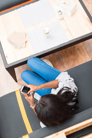 african american woman using smartphone while sitting in cafeの写真素材