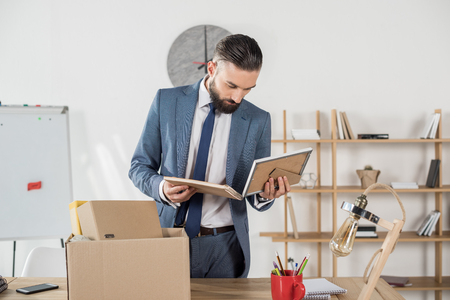 fired upset businessman looking at photos at workplace in officeの写真素材