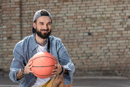 smiling hipster man holding basketball ball in handsの写真素材