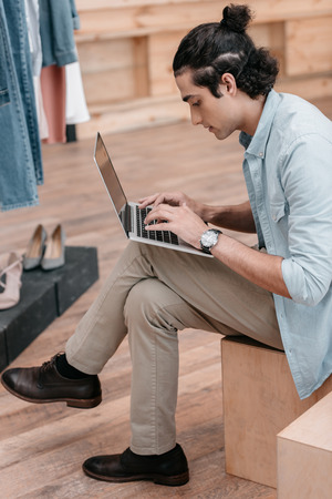 young shop owner using laptop while sitting indoors before openingの写真素材