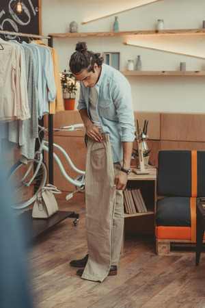 young business owner hanging and selecting clothes before opening in boutiqueの写真素材