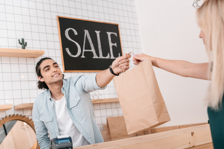 seller giving shopping bag to client in boutiqueの写真素材