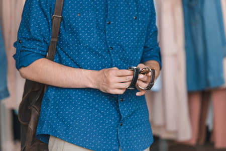 stylish young man choosing wristwatches in boutiqueの写真素材