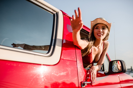 woman waving out of car windowの写真素材