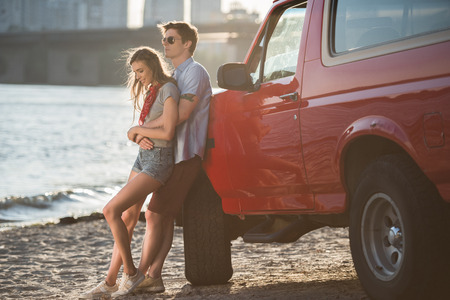 young couple hugging near car