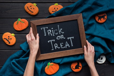 woman holding frame with trick or treat inscription for halloweenの写真素材