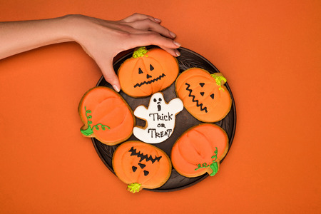 top view of woman taking halloween cookie from plateの写真素材