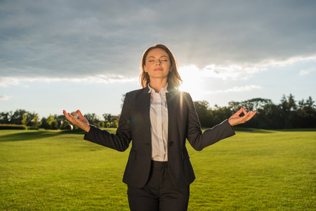 smiling businesswoman meditating in parkの写真素材