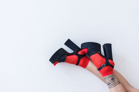 cropped view of female feet in red socks and fashionable heels, isolated on whiteの写真素材
