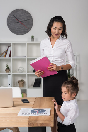 asian businesswoman with daughter in officeの写真素材