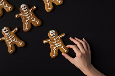 cropped shot of human hand with halloween cookies in shape of skeletonsの写真素材