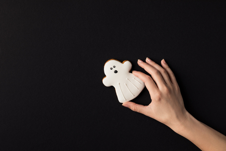 cropped shot of human hand with halloween cookie in shape of ghostの写真素材