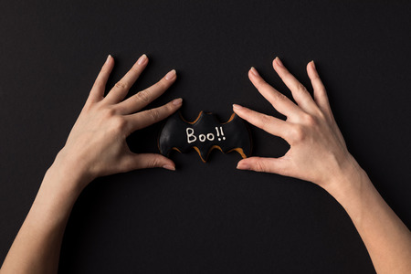 cropped shot of human hands with halloween cookie in shape of batの写真素材