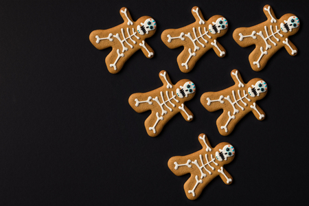 top view of spooky halloween skeleton cookies isolated on black
