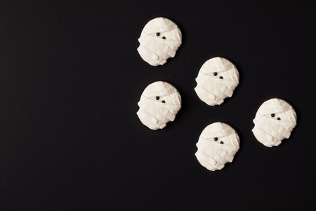close-up top view of spooky halloween mummy cookies isolated on blackの写真素材