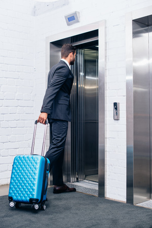 businessman with suitcase entering elevatorの写真素材