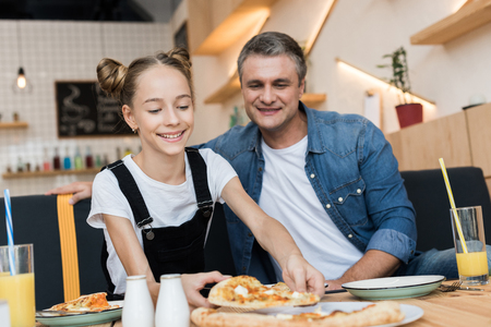 father and daughter eating pizzaの写真素材