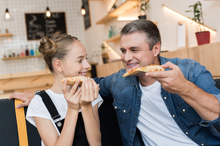 father and daughter eating pizzaの写真素材