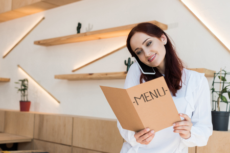 woman talking by phone and looking at menuの写真素材
