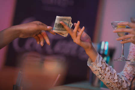 woman paying barman for cocktails