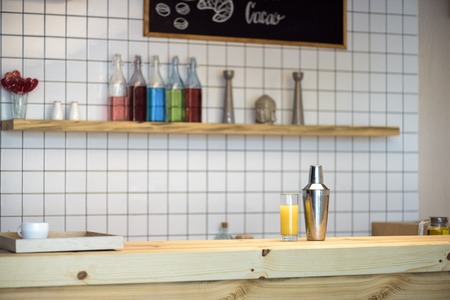coffee cup on tray, shaker and glass with juice on bar counterの写真素材