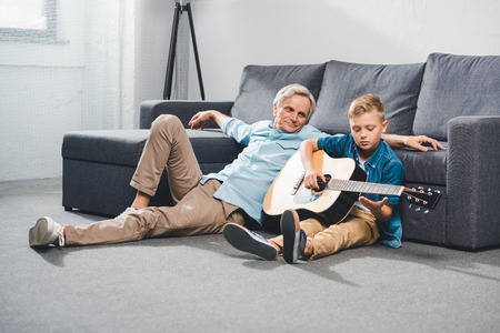 grandfather and grandson playing on guitarの写真素材