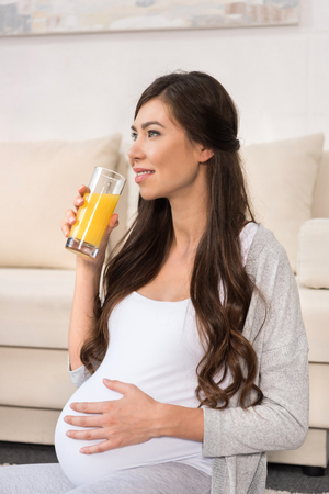 Pregnant woman drinking glass of juiceの写真素材