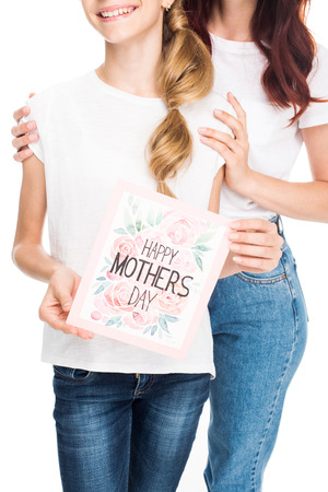 cropped view of mother and daughter with happy mothers day greeting card, isolated on whiteの写真素材