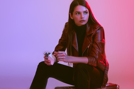 smoking girl sitting on suitcaseの写真素材