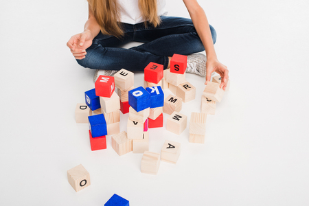 cropped view of child playing with alphabet blocks, isolated on whiteの写真素材