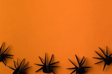 black origami spiders for halloween, isolated on orange with copy spaceの写真素材