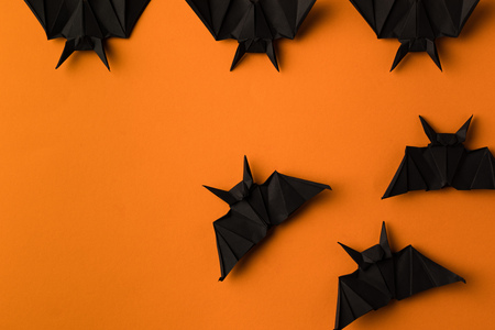 black origami bats for halloween, isolated on orange with copy space