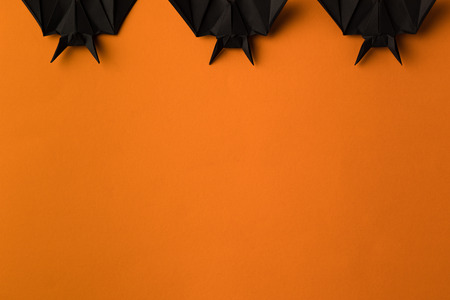 black origami bats for halloween, isolated on orange with copy spaceの写真素材