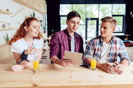 friends with digital tablet in cafeの写真素材