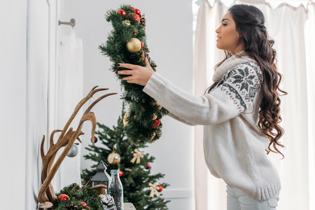 woman hanging christmas wreath over fireplaceの写真素材