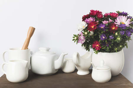 various ceramic cookware, wooden pestle and flowers in vase on table