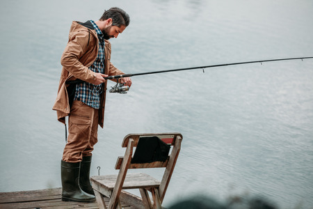 man fishing with rod on pier