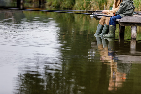 father and son fishing on lakeの写真素材