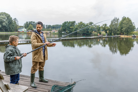 father and son fishing on lakeの写真素材