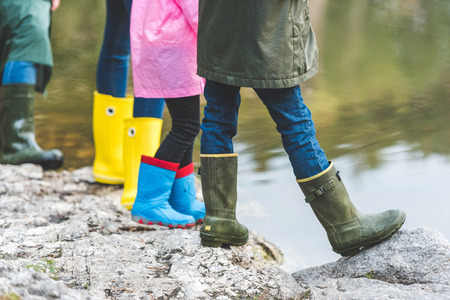 family in rubber boots standing on rockの写真素材