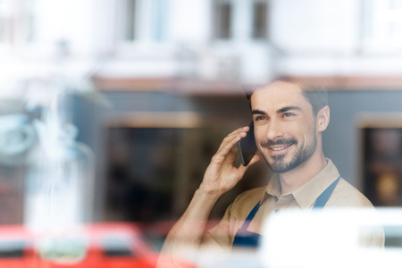 man in apron talking on smartphone