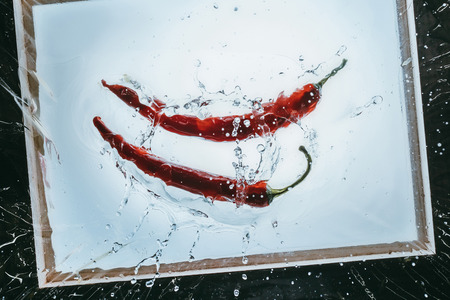 fresh chili peppers floating in water with splashの写真素材