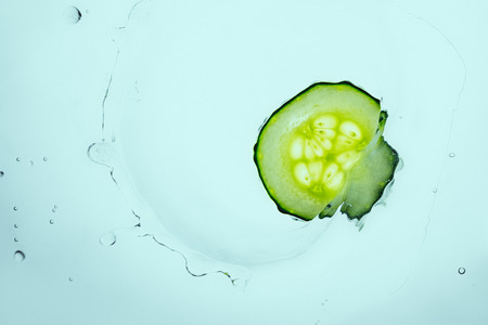 fresh cucumber slice floating in water with splashの写真素材
