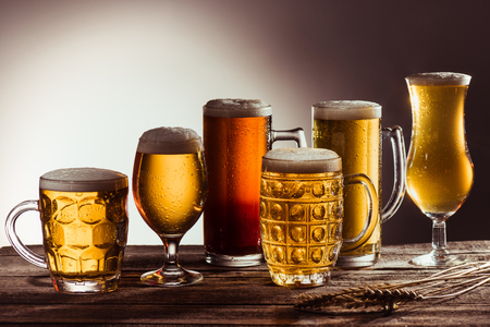 assortment of beer in glasses on wooden tabletop with wheat earsの写真素材