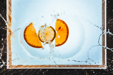 fresh slices of orange and lemon floating in water with splashの写真素材