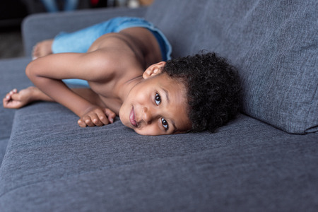 shirtless little kid playing on sofaの写真素材